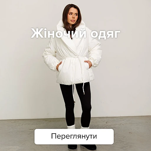 Жінка в теплій білій куртці з об'ємним коміром, поясом та кишенями, чорних легінсах та темному взутті.