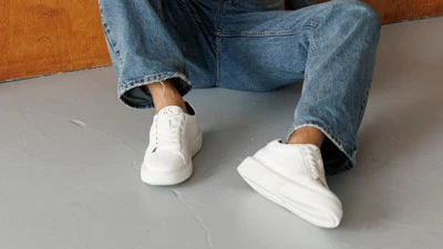 Чоловічі літні шкіряні кеди білого кольору на моделі в джинсах