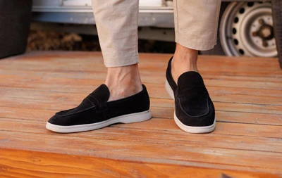 Мужские замшевые лоферы черного цвета с белой подошвой, вид сбоку на деревянной террасе