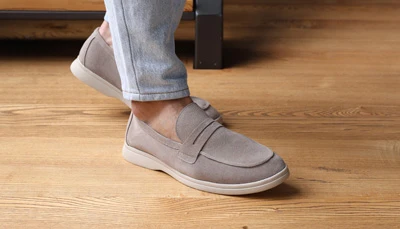 Мужские бежевые замшевые лоферы 40 размер со светлой подошвой, вид сбоку на деревянном полу