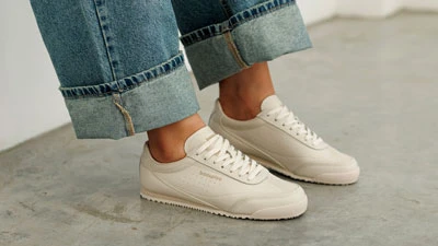 Женские белые весенние кроссовки на ногах в джинсах