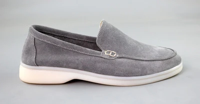 Жіночі сірі замшеві лофери на білій підошві, вид збоку на сірому фоні