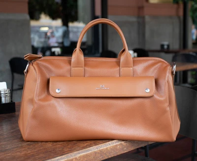 Жіноча рудого кольору шкіряна сумка з короткими ручками на дерев'яному столі