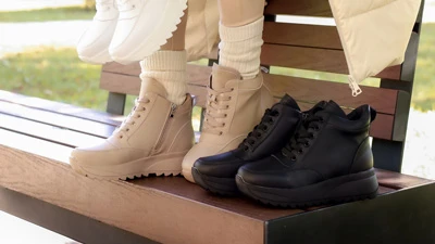 Женские кроссовки на молнии: бежевые на ноге и черные рядом на скамейке, осенний образ