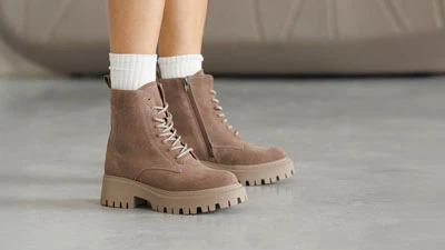 Замшевые женские сапоги к лодышке светло-коричневого цвета со шнуровкой спереди, боковой молнией и массивной подошвой на платформе. На ногах – белые носки. Осенне-зимний стиль.