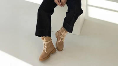 Женские зимние бежевые полусапожки на шнуровке с тракторной подошвой, на модели в темных джинсах сидя