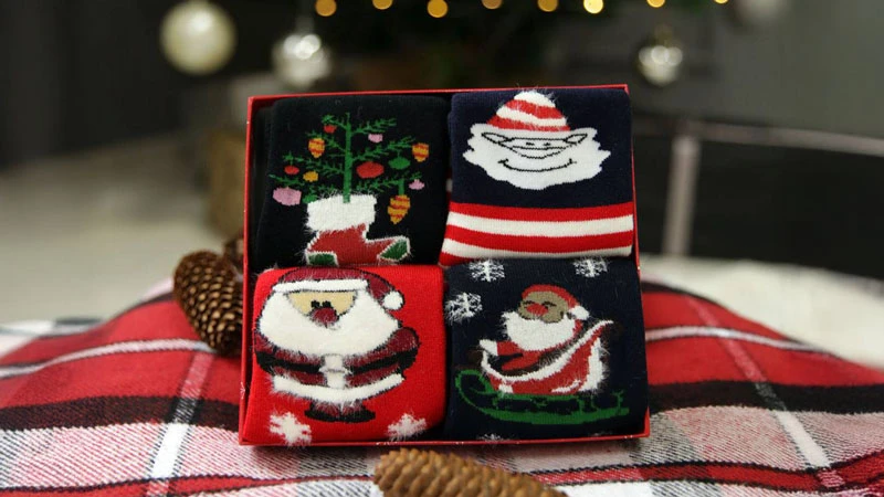 Подарунковий набір новорічних шкарпеток із Сантою на фоні святкового пледа