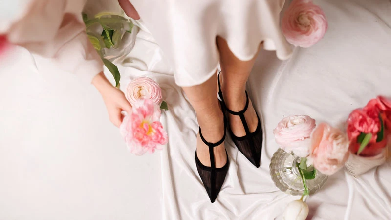 Черные женские туфли с острым носком, сетчатыми вставками и T-образным ремешком среди весенних цветов