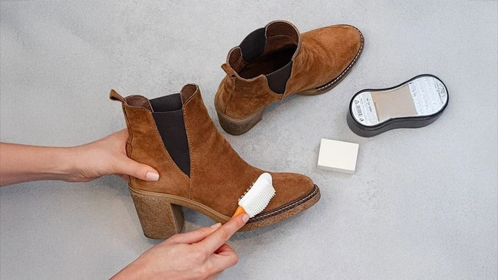 Очищення коричневих замшевих черевиків спеціальною щіткою